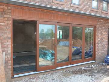 Installation of G BARNSDALE Red brandish hardwood Bi folding doors. The Timber Folding doors come with a flush floor aluminium track. |Our Timber Bi folds our fabricated in Red GRANDIS hardwood. Red GRANDIS is a light coloured hardwood which can be stained to a selection of finish the Bi folding doors in the picture our stained Teak. Our Cheshire based window and door tem carried out the contract in 1 day